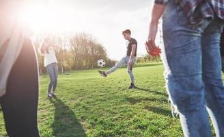 een groep vrienden in casual outfit voetballen in de open lucht. mensen veel plezier en plezier. actieve rust en schilderachtige zonsondergang foto