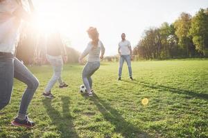 een groep vrienden in casual outfit voetballen in de open lucht. mensen veel plezier en plezier. actieve rust en schilderachtige zonsondergang