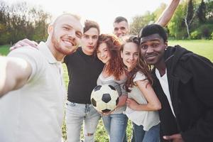 een groep vrienden in casual outfit doen sephi op het voetbalveld. mensen veel plezier en plezier. actieve rust en schilderachtige zonsondergang foto