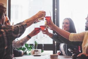 groep jonge vrienden die plezier hebben en lachen tijdens het dineren aan tafel in restaurant foto