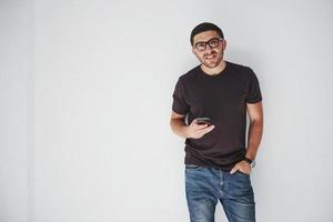 jonge gelukkige man casual gekleed met slimme telefoon op witte achtergrond
