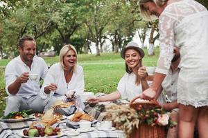 wat heb je ons gebracht. groep volwassen vrienden rusten en praten tijdens het eten in de achtertuin van het restaurant foto