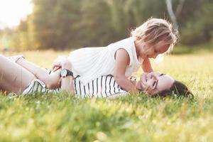 op het gras gaan liggen. mooi portret van meisje en haar dochter omhelzen elkaar buiten foto