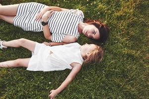 bovenaanzicht van kinderen en moeder die op het gras vol zonneschijn liggen en naar elkaar kijken