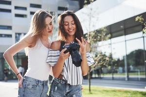 twee mooie, mooie vrienden van het meisje met de camera maken samen foto's en wandelen door de stad foto