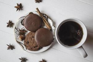 een kop van koffie met chocola koekjes, Aan een wit houten tafel. foto