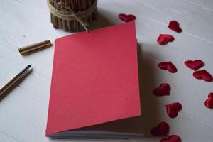 rood notitieboekje, kaars en liefde harten Aan een bureau. foto