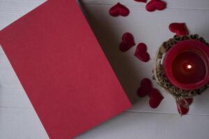 rood notitieboekje, kaars en liefde harten Aan een bureau. foto