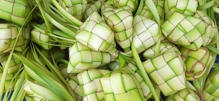 ketupat of rijst- knoedel. een traditioneel rijst- behuizing gemaakt van jong kokosnoot bladeren voor Koken rijst- verkocht in traditioneel markt voorbereiding voor de eid al-fitr vakantie voor moslim foto