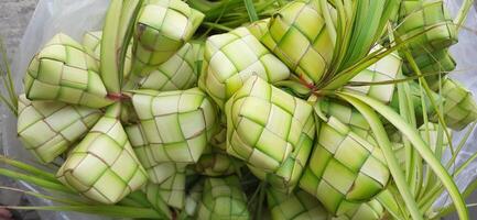 ketupat of rijst- knoedel. een traditioneel rijst- behuizing gemaakt van jong kokosnoot bladeren voor Koken rijst- verkocht in traditioneel markt voorbereiding voor de eid al-fitr vakantie voor moslim foto