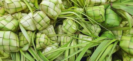 ketupat of rijst- knoedel. een traditioneel rijst- behuizing gemaakt van jong kokosnoot bladeren voor Koken rijst- verkocht in traditioneel markt voorbereiding voor de eid al-fitr vakantie voor moslim foto