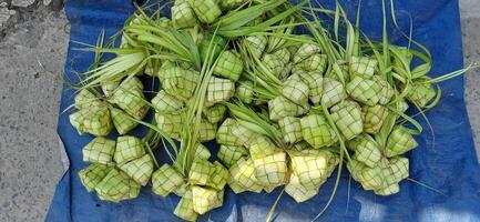 ketupat of rijst- knoedel. een traditioneel rijst- behuizing gemaakt van jong kokosnoot bladeren voor Koken rijst- verkocht in traditioneel markt voorbereiding voor de eid al-fitr vakantie voor moslim foto