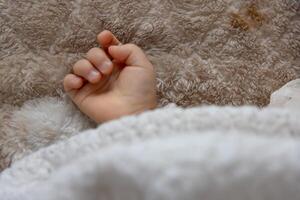 een Rechtsaf hand- van slapen Aziatisch baby Aan de tapijt foto
