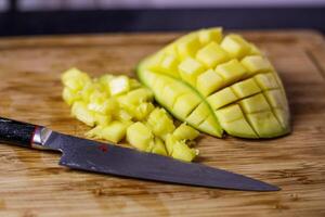 persoon met zwart handschoenen snijdend en snijden mango voor smoothie hout snijdend foto