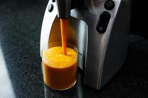 mango wortel appel smoothie in een glas Aan donker achtergrond met glas rietje foto