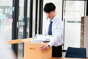 een Mens in een pak is opening een karton doos Aan een bureau foto