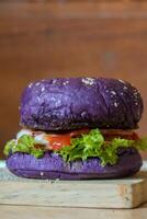 dichtbij omhoog foto van een eigengemaakt Purper hamburger geplaatst Aan een keramisch tafel