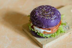 dichtbij omhoog foto van een eigengemaakt Purper hamburger geplaatst Aan een keramisch tafel