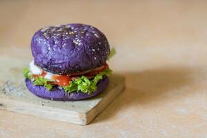 dichtbij omhoog foto van een eigengemaakt Purper hamburger geplaatst Aan een keramisch tafel