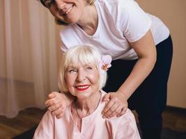 senior blanke stijlvolle vrouw met grijs haar en roze phalaenopsis in haar haar zittend op thaise massage. anti-leeftijd, gezonde levensstijl, reizen, thais massageconcept foto