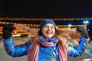 gelukkig lachende jonge blanke vrouw in sjaal, muts, jas, wanten door de buitenbaan. nieuwjaar, plezier, winterconcept foto