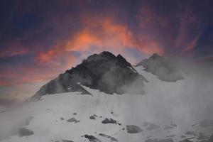 steile berg met zonsonderganghemel foto