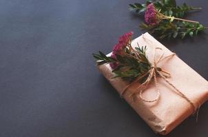 ambachtelijke geschenkdoos met knoop natuurlijk met roze bloemetjes op zwarte achtergrond. foto