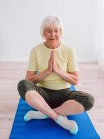 senior vrouw doet yoga online binnen. anti leeftijd, sport, technologie, yoga concept foto