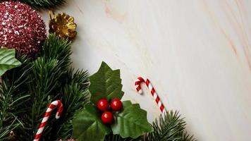 groene dennenboombladeren, roze kerstversieringen en zuurstokken op zachte marmeren achtergrond, kerstversieringen in heldere en mooie roze kleur. eenvoudig en creatief kerstconcept. foto