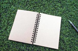 kraftpapier spiraal notebook met pen op het kunstgras foto