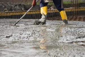 metselaar die het vers gestorte beton egaliseert om de fundamenten van een gebouw te leggen foto