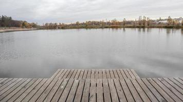 een kleine houten pier op een rustig meer in de mistige herfstochtend. foto