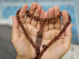 een jong Aziatisch moslim vrouw houdt gebed kralen en bidt gedurende de vastend maand van Ramadan foto