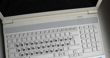 top visie van laptop met ijzer noten bedekking een Russisch brieven Aan toetsenbord toetsen foto