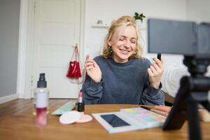 portret van jong inhoud maker, vrouw blogger opname een Aan digitaal camera, tonen lippenstift kleur naar haar volgers, creëren levensstijl vlog voor sociaal media account foto