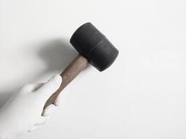 man's hand- met handschoenen houdt een rubber hamer geïsoleerd Aan wit achtergrond.timmerman gereedschap concept. foto