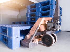 hand- pallet jack en sommige blauw pallet Aan de distributie magazijn Oppervlakte. foto