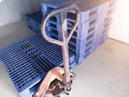 hand- pallet jack en sommige blauw pallet Aan de distributie magazijn Oppervlakte. foto