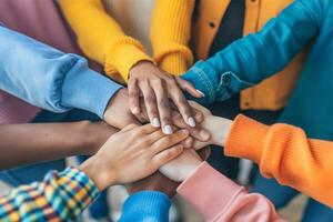 multi-etnisch groep van jong mensen zetten hand- samen, concept van solidariteit en werken samen, hand- samen foto