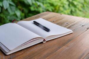Open wit leeg papier kladblok Aan houten tafel buitenshuis. concept van auteur schrijven in ontspannen knus atmosfeer. geestelijk Gezondheid digitaal ontgiften vertragen naar beneden praktijken foto