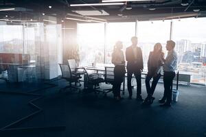 bedrijf team staand tegen panoramisch ramen in modern kantoor foto