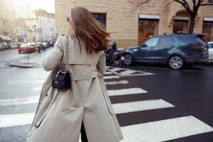 terug visie van vrouw in modieus outfits kruisen weg tegen backdrop van stad gebouwen foto