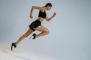 vastbesloten sportief vrouw rennen in in de lucht oefenen gedurende cardio training over- studio achtergrond foto