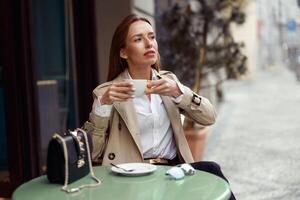 elegant jong vrouw drinken koffie Aan restaurant terras en op zoek Bij kant foto