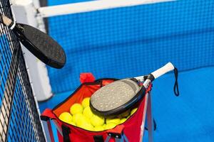 peddelen tennis racket en ballen Aan de blauw peddelen rechtbank foto