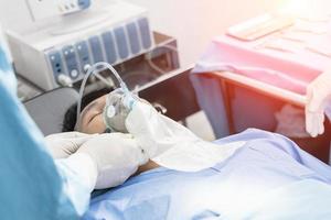 assistent-chirurg zette de patiënt op een beademingszuurstofmasker ter voorbereiding op de operatie. foto