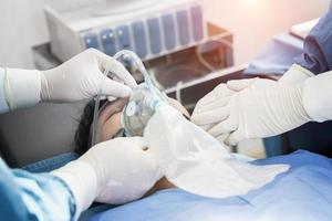 assistent-chirurg zette de patiënt op een beademingszuurstofmasker ter voorbereiding op de operatie. foto