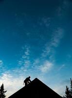 aannemer in silhouet bezig met een dak foto