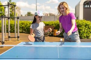 jong vrouw met haar dochter spelen ping pong in park foto