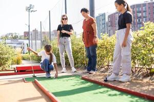 familie spelen mini golf Aan een reis voering. kind hebben pret met actief vrije tijd Aan vakanties. foto